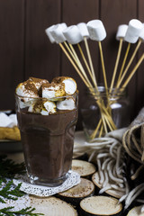 a cup of cocoa with marshmallow on a wooden table next to a rug and sweets