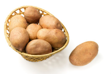 Uncooked, fresh crop of potatoes in a wicker basket isolated on white background, close-up view