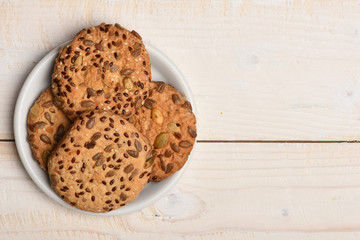 Oatmeal cookies with seeds on white old wooden table