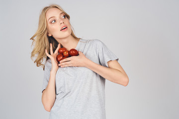 girl surprises with tomatoes in her hands on a light background