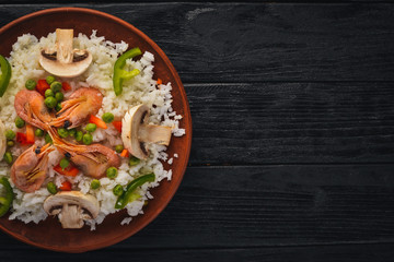 Risotto with shrimp and vegetables. Seafood. Asian cuisine. On a wooden texture background. Top view. Free space.