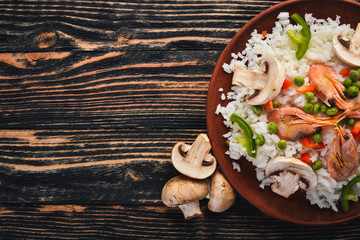 Risotto with shrimp and vegetables. Seafood. Asian cuisine. On a wooden texture background. Top view. Free space.