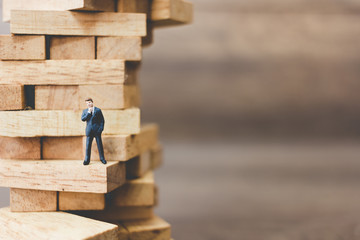 Miniature people: Businessman standing on wood block