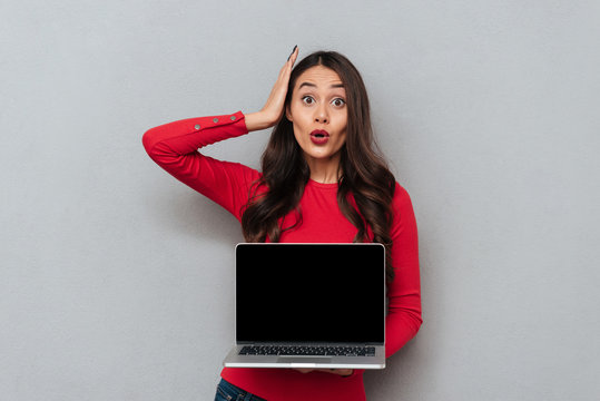 Brunette woman in red blouse showing blank laptop computer screen