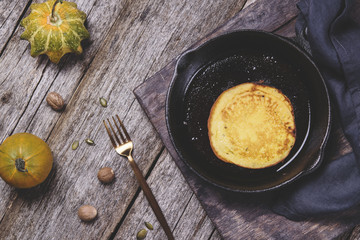 Homemade pumpkin pancakes on cast iron frying pan on vintage wooden table. Fall's breakfast. Selective focus. Haze effect 