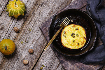 Homemade pumpkin pancakes on cast iron frying pan on vintage wooden table. Fall's breakfast. Selective focus 