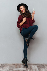 Full length image of cheerful brunette woman in sweater