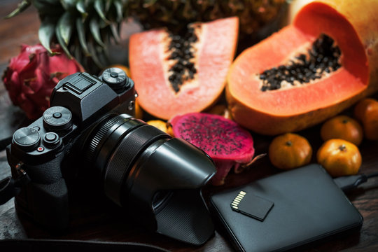 Tropical fruit near modern laptop and photocamera on wooden background. Tools for photo blogger anr travel journalist. Up view