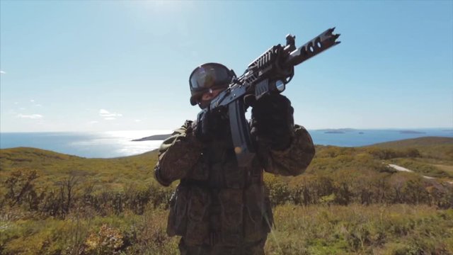 Portrait of a soldier with AK. Soldier aiming at the enemy. Seascape on background.
