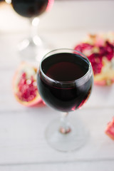 Organic pomegranate wine on white wooden table.