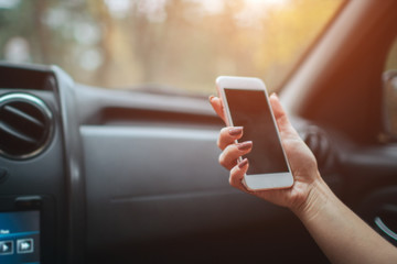 eautiful woman smiling while sitting on the front passenger seats in the car. Girl is using a smartphone. Hand closeup