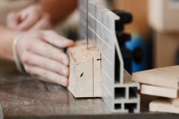 Fototapeta premium Carpenter - only hands to be seen - is standing on electric cutter; close up on the component part