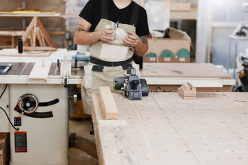 carpenter puts on goggles and is going to work at an electric plane in a joiner's workshop...