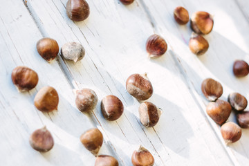 Fresh raw chestnuts on white wooden surface.