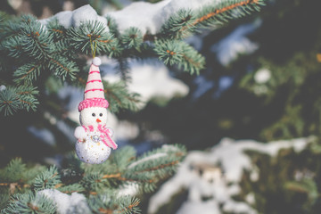Christmas background Snowman sitting on snow-covered branches of a Christmas tree