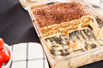 Tiramisu cake in an oven pan on a dark wooden table