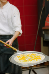 Uncooked pizza on the pizza shovel on the italian restaurant kitchen.