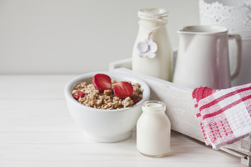 Ready breakfast - granola with a fresh ripe strawberry and milk with a miniature bottle. Close-up,...