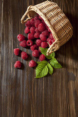 Ripe sweet raspberries in a bowl on a white wooden table. Close-up, top view, natural healthy product