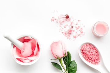 Make cosmetics with rose  oil. Mortar with rose petals and pestle on white background top view copyspace