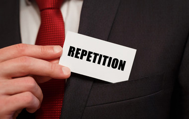 Businessman putting a card with text REPETITION in the pocket