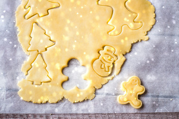 Raw dough on wooden board with rolling pin and cookie cutters in Christmas shapes. Preparation of Holiday Cookies