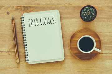 Fototapeta na wymiar Top view 2018 goals list with notebook, cup of coffee on wooden desk.
