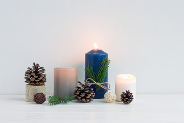 Fototapeta na wymiar Christmas dark blue candles, wood slice decorations, pine cone on white background