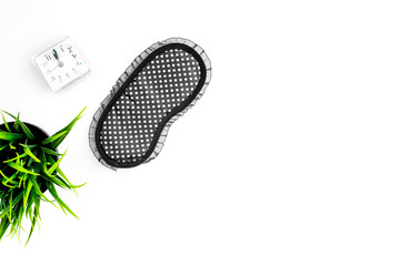 Healthy sleep concept. Sleep mask, plant, alarm clock on white background top view copyspace
