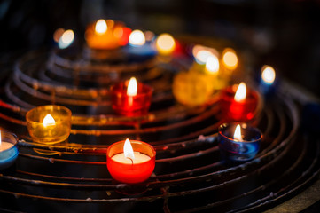 Burning candles in colorful candle holders in a church