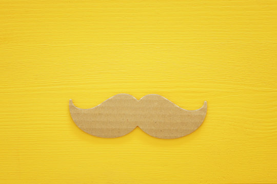 Top view image with paper moustache over wooden background