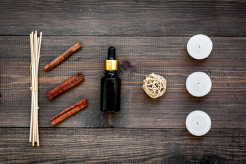 Skin care and relax. Cosmetics and aromatherapy concept. Oil and candles with spices cinnamon on dark wooden background top view