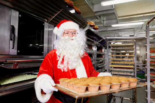Santa Claus baker with a tray of cupcakes in his hands during Christmas.