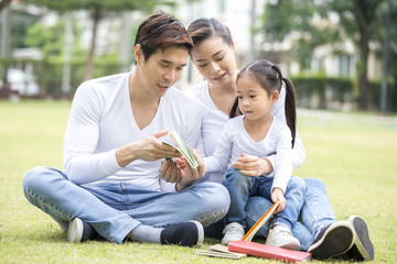 Asian family reading book together at outdoor place. People lifestyle concept.