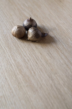 Black Garlic Bulbs on Wood Surface