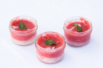 Three Raspberry desserts in glass cups decorated with mint leaves