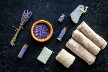 Set for foot spa with lavender. Flowers, spa salt, pumice stone, soap on black background top view