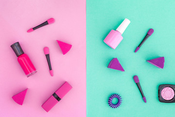 Cosmetics on colorful background. Pink and violet nail polish and lipstick on pink and mint background top view