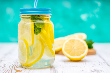 Banks with handles with cold lemonade on a white wooden background. Lemons.