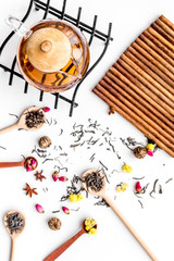 Brew tea with flowers and spices. Dried leaves and petals near tea pot on white background top view