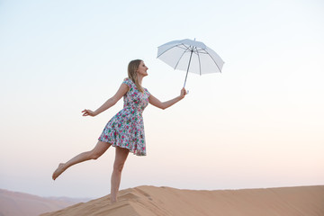 Young woman posing with an umbrella in the desert.
