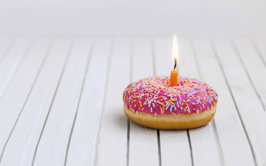 Birthday donut with pink glaze and colorful candies and burning candle , birthday concept