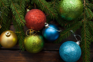Obraz na płótnie Canvas New Year's green balls with fir branches on a wooden background. Top view