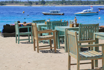 Verwitterte blaue Tische und Stühle eines Restaurants am Strand der Insel Trawangan, Gili Islands (Indonesien)