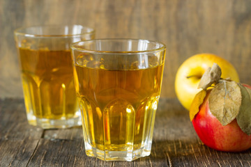 Apple juice in glasses and fresh apples on a wooden background. Rustic style.