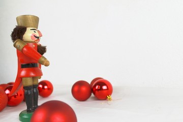 seitlich stehender Nussknacker und rotee Weihnachtsbaumkugeln