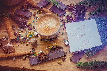 New Year's winter composition with coffee and spices in the kitchen on a wooden dinette and with pine branches. Beauty and inspiration with winter desserts.