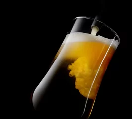 Foto op Plexiglas bier gegoten in een glas op een zwarte achtergrond © venge