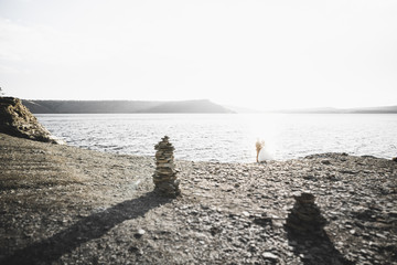 Wedding couple kissing and hugging on rocks near blue sea