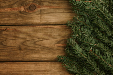 Green needles branch on wooden desks. Empty copy space christmas background.